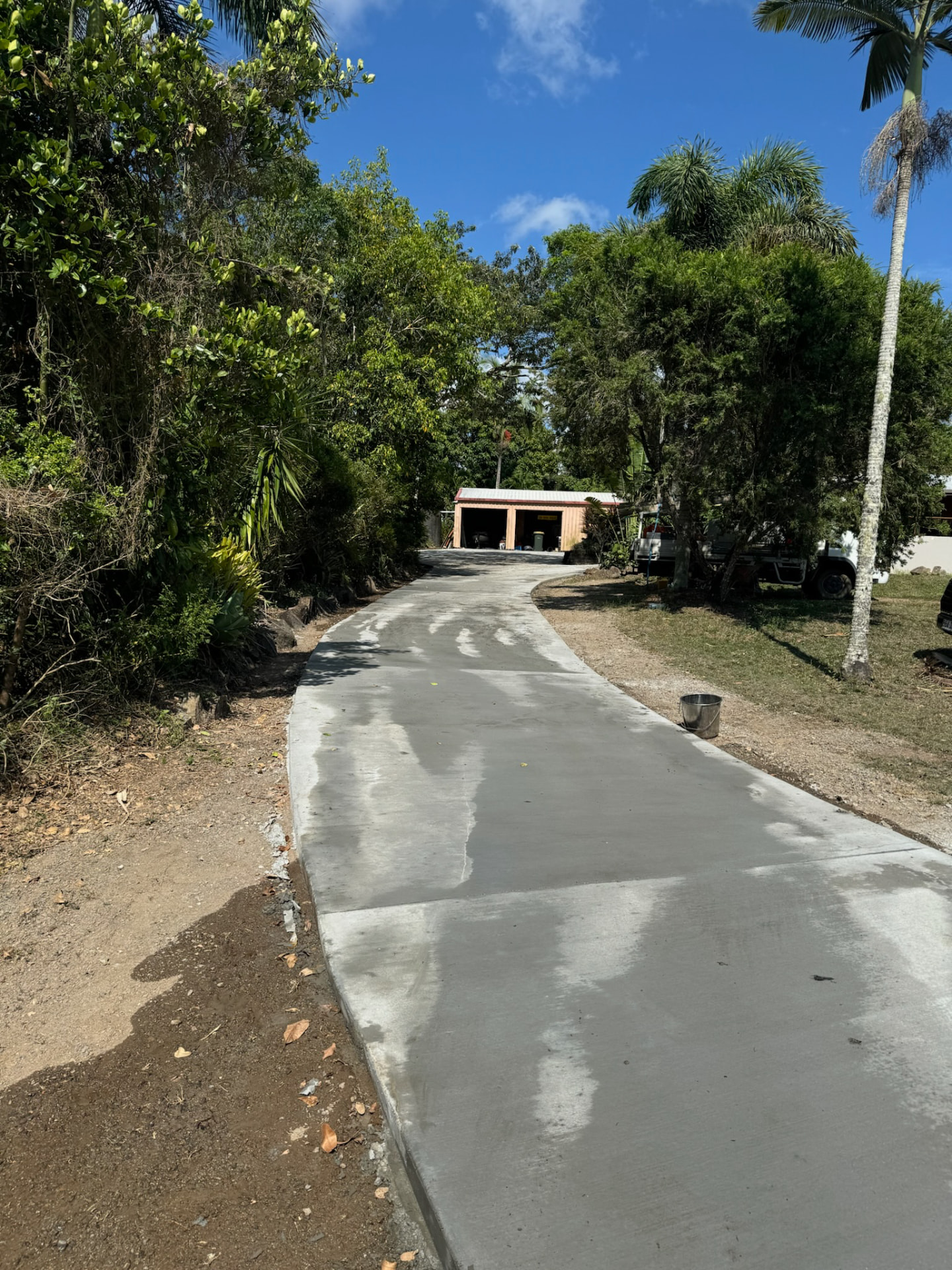 Finished plain concrete driveway through a tropical garden